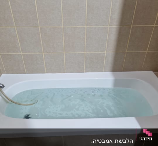 אמבטיה עם מים וקירות מחופים באריחים
